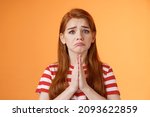Small photo of Pity uneasy redhead girl pull sad face, quivering lip upset, begging mercy, apologizing, plead help, press palms pray gesture, frowning hopeless, asking and begging favour, stand orange background