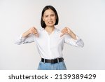 Small photo of Dislike. Disgusted asian woman showing thumbs down and grimacing, commenting on smth bad, disagree, complaining, standing over white background