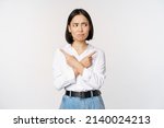 Small photo of Indecisive asian woman pointing fingers sideways, pointing fingers and looking clueless, confused with choices, standing over white background
