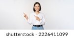 Small photo of Image of smiling young office lady, asian business entrepreneur pointing fingers left, showing client info, chart of banner aside on copy space, white background.