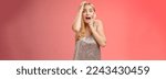 Small photo of Shocked terrified blond woman horrified see crime screaming pop eyes shouting hold hands head afraid trembling fear standing frightened drop jaw gasping face terrible accident, red background.
