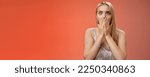 Small photo of Concerned shocked worried blond woman terrified gasping cover mouth hands pray gesture widen eyes witness terrible accident worry expressing empathy pity, standing red background uneasy.