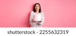 Small photo of Cute asian girlfriend congratulate with valentines day, giving cute romantic gift in box, pucker lips for kiss, standing over pink background.