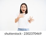 Small photo of Image of scared asian woman, looking worried and concerned, terrified shouting, standing over white background.