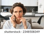 Small photo of Close up portrait of woman talking on mobile phone with troubled face, listening to complicated conversation, thinking while calling someone.
