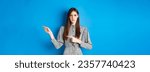 Small photo of Angry frowning woman pointing fingers right and condemn person, feeling disapointed, standing in dress on blue background.