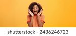Small photo of Waist-up shot of impressed excited talkative dark-skinned woman with curly hair and perfect skin yelling from happiness and amazement shaking palms near face cheering for awesome sale over orange wall