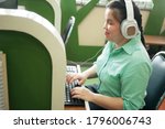 Small photo of Disability young blind person happy woman in headphone typing on computer keyboard working in creative workplace office.