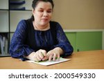 Small photo of Asian blind person woman hands writing braille by using slate and stylus tools making embossed printing for Braille character encoding. Braille is a system of raised dots for vision disability people.