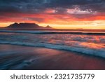 Table Mountain at sunset from Blouberg Beach with waves rolling in