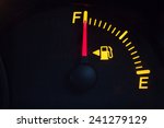 Fuel gauge showing a full tank. Yellow glowing meter with a red needle. Isolated against black background.