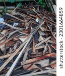 Small photo of A pile of wooden waste material lies in disarray, discarded and forgotten. The scraps of wood are of various sizes and shapes, some are long and slender while others are thick and cumbersome. The roug