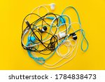 Bunch of different earphones isolated on yellow background. Color conceptual. Conceptual minimalism. Minimal thing. Minimal think. Tangling bunch of earphones wires. Tangled cable