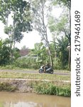 Small photo of Vehicle passing on road or sepeda motor lewat di jalan inspeksi selokan mataram, saluran irigasi pertanian yang panjang dibangun atas prakarsa Raja Jogja di, yogyakarta, Indonesia, July 18, 2022