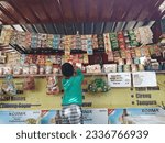 Small photo of Children buy food at a stall, Indonesia, July 25, 2023, anak anak sedang jajan di warung, food court, menjual roti, snack, gorengan, mie, permen, nutrisari, kopi, cireng,tahu walik, tempura nasi rames