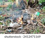 Small photo of burning out the garbage, Indonesia, January 14,2024 burning rubbish, plastic, inorganic, burnt, with fire, in an open area, the fire engulfs the rubbish, white smoke billows, the rubbish is completely