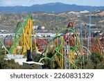 Wide view of colorful roller coaster rides at an amusement park, sunny day mountains in background. Six Flags Magic Mountain Six Flags Hurricane Harbor