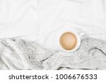 Cup of coffee on bed with warm plaid. Copy space. Flat lay, top view