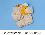 Kids warm puffer jacket with yellow  hat on blue background. Stylish childrens outerwear. Winter fashion outfit 
