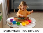 A little girl playing colored rice and make rainbow. Child filled the rainbow with bright rice. Montessori material. Sensory play and learning colors activity for kids. 