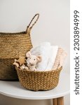 Small photo of Stack of baby clothes with cute little toy mouse in the basket and accessories for newborn. Cotton clothes and muslin swaddle blanket in pastel colors. Clean freshly laundered, neatly folded clothes.