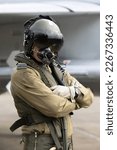 Small photo of Military Fighter Pilot with helmet, visor and oxygen mask in flying suit with fighter jet.