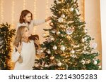 Little girl and her mom decorating Christmas tree together