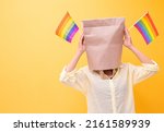 Pride month Cheering anonymous people girl with shopping bag head.holding in hands covering ,LGBT,LGBTQ flag having fun celebrating isolated over yellow background.Sexual equality,Gay flag,Lesbian.
