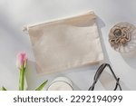Small photo of Canvas pouch mock-up. Beige cosmetic bag and feminine accessories on the table, top view