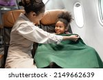 Small photo of Happy air hostess take care passenger kid girl of gave blanket cover