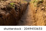 Small photo of Dig a trench. Earthworks, digging trench. Long earthen trench dug to lay pipe or optical fiber. Construction the sewage and drainage. View from the trench. Clay soil