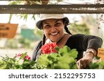 Small photo of Short, heavy-set Latina woman working in her botanical garden with a hat on her head, very happy.