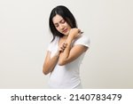 Asian women have skin problems She felt irritation on her skin. Skin infection itching red rash scratching with hands. She around 25 Wearing white shirt standing on isolate background