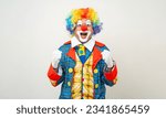 Small photo of Mr Clown. Portrait of Funny shocked face comedian Clown man in colorful costume wearing wig standing posing smiling to camera. Happy expression amazed bozo in various pose on isolated background.