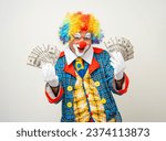 Small photo of Mr Clown. Portrait of Funny face Clown man in colorful uniform standing holding a lot of money for gambling. Happy expression male bozo in various pose on isolated background.