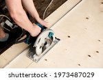 Small photo of Sawing plywood by circular saw. Home repair. Hand tool. Man hold equipment. Building process. Woodworking. Safety engineering. Without gloves. Copy space. Indoor. Cutting material. Rental instrument.