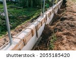 Timber formwork with metal reinforcement with pour concrete and creating a solid foundation for a building or fence. Construction process. Building the retaining wall. Side view. Nobody. Copy space.