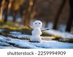 Small photo of A small melting snowman in a clearing with melting snow and sun spots. The coming of spring. Warming.