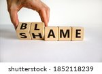 Small photo of Blame or shame. Male hand flips wooden cubes and changes the inscription 'shame' to 'blame' or vice versa. Beautiful white background, copy space.