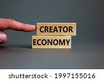 Creator economy symbol. Wooden blocks with words Creator economy on beautiful grey background, copy space. Businessman hand. Business and creator economy concept.