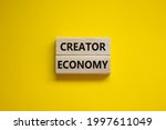 Creator economy symbol. Wooden blocks with words Creator economy on beautiful yellow background, copy space. Business and creator economy concept.