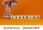 Small photo of Hybrid or in-class learning symbol. Businessman turns cubes, changes words hybrid learning to in-class learning. Orange background. Education and hybrid or in-class learning concept. Copy space.