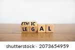 Small photo of Ethical or legal symbol. Turned wooden cubes and changed the word 'legal' to 'ethical' on a beautiful wooden table, white background. Business and ethical or legal concept. Copy space.