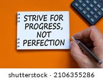 Progress or perfection symbol. Businessman writing words Strive for progress, not perfection on white note. Black calculator. Orange background. Business, progress or perfection concept. Copy space.