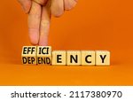 Small photo of Efficiency or dependency symbol. Businessman turns cubes, changes the word dependency to efficiency. Beautiful orange table, orange background, copy space. Business, efficiency or dependency concept.
