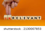Small photo of Relevant or irrelevant symbol. Businessman turns wooden cubes changes the word irrelevant to relevant. Beautiful orange table orange background. Business, relevant or irrelevant concept. Copy space.