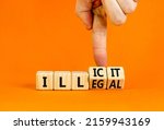 Illegal or illicit symbol. Businessman turns wooden cubes and changes the concept word Illegal to Illicit. Beautiful orange table and background. Business and illegal or illicit concept. Copy space.
