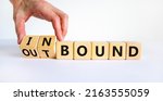 Small photo of Inbound or outbound symbol. Businessman turns wooden cubes and changes the word 'outbound' to 'inbound'. Beautiful white table, white background. Business, inbound or outbound concept. Copy space.