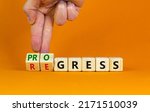 Small photo of Regress or progress symbol. Businessman turns wooden cubes and changes the word 'regress' to 'progress'. Beautiful orange table, orange background, copy space. Business, regress or progress concept.