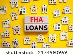 Small photo of FHA federal housing administration loans symbol. Concept words 'FHA federal housing administration loans' on wooden blocks on a beautiful yellow background. Business and FHA loans concept. Copy space.